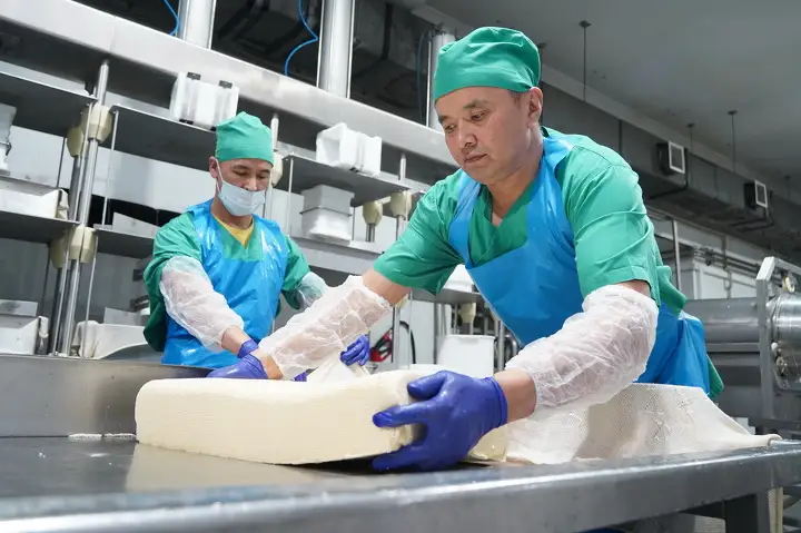 Работники переворачивают головки сыра