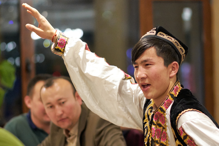Мужчина танцует уйгурский танец в ресторане Пекина