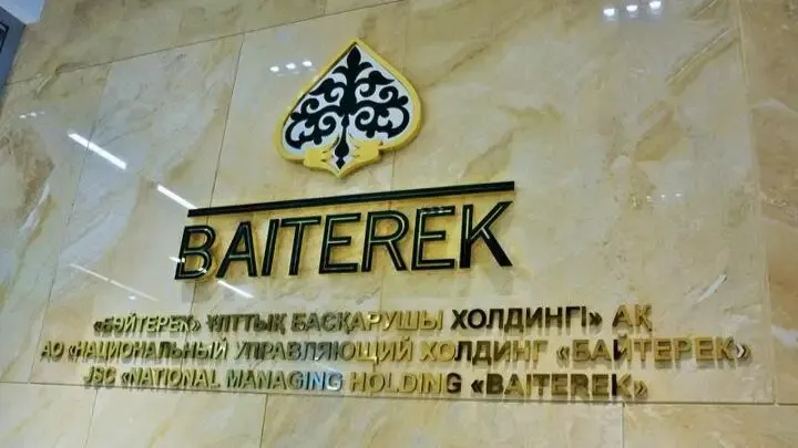 Логотип холдинга «Байтерек» на стене с надписью «АО «Национальный управляющий холдинг «Байтерек» на казахском, русском и английском языках