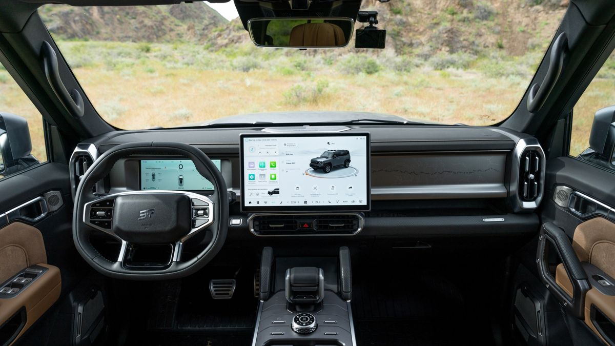 Панель управления JETOUR T2, руль и планшет управления автомобилем, в лобовом стекле - степной пейзаж 