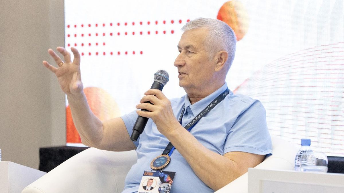Сергей Бушуев, седой мужчина с микрофоном сидит в белом кресле