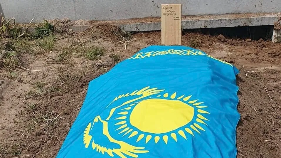 Последнее пристанище Айдоса Садыкова Свежая могила, могильный холм, укрытый голубым флагом Казахстана.