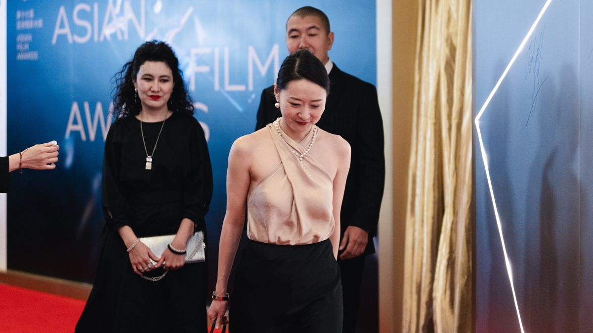 Акмарал Мерген , Юлия Ким и Азамат Дулатов на награждении Asian Film Awards, три человека на фоне надписи 