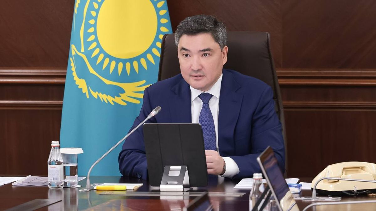 Премьер-министр Казахстана Олжас Бектенов выступает на заседании правительства РК сидит за коричневым столом на фоне флага РК