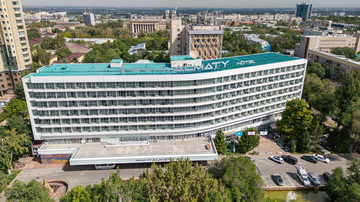 Здание гостиницы Алматы сверху, зеленая крыша, логотип 
