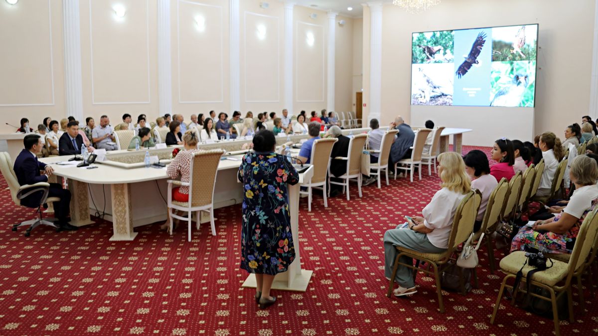 Международный семинар в Лисаковске, участники на стульях в зале с красным ковром