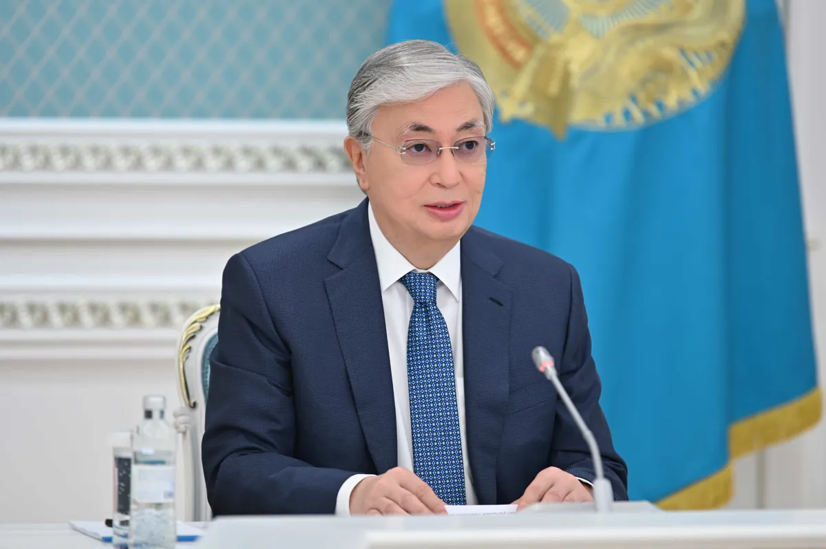 Касым-Жомарт Токаев на фоне флага Казахстана