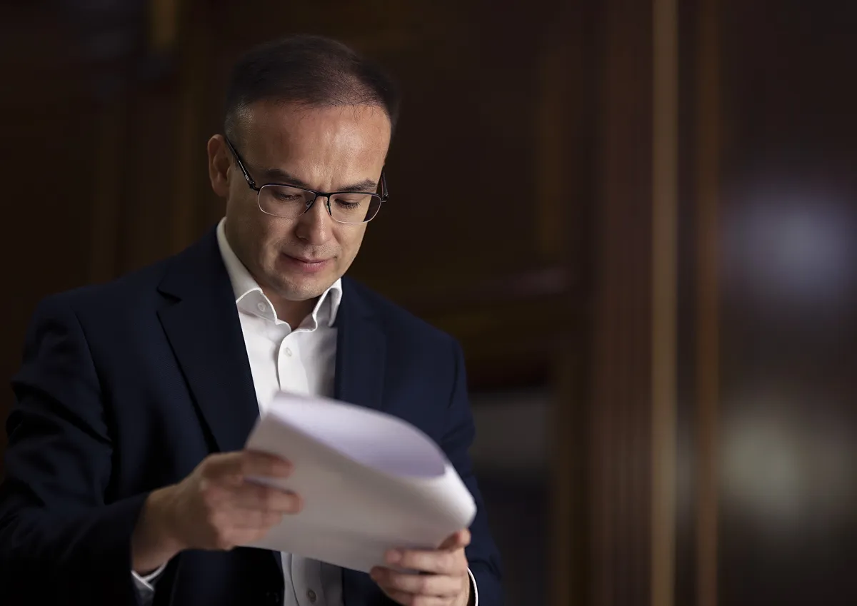Бекжан Пирматов Бекжан Пирматов стоит с листами бумаги в руках, читает документы, в очках