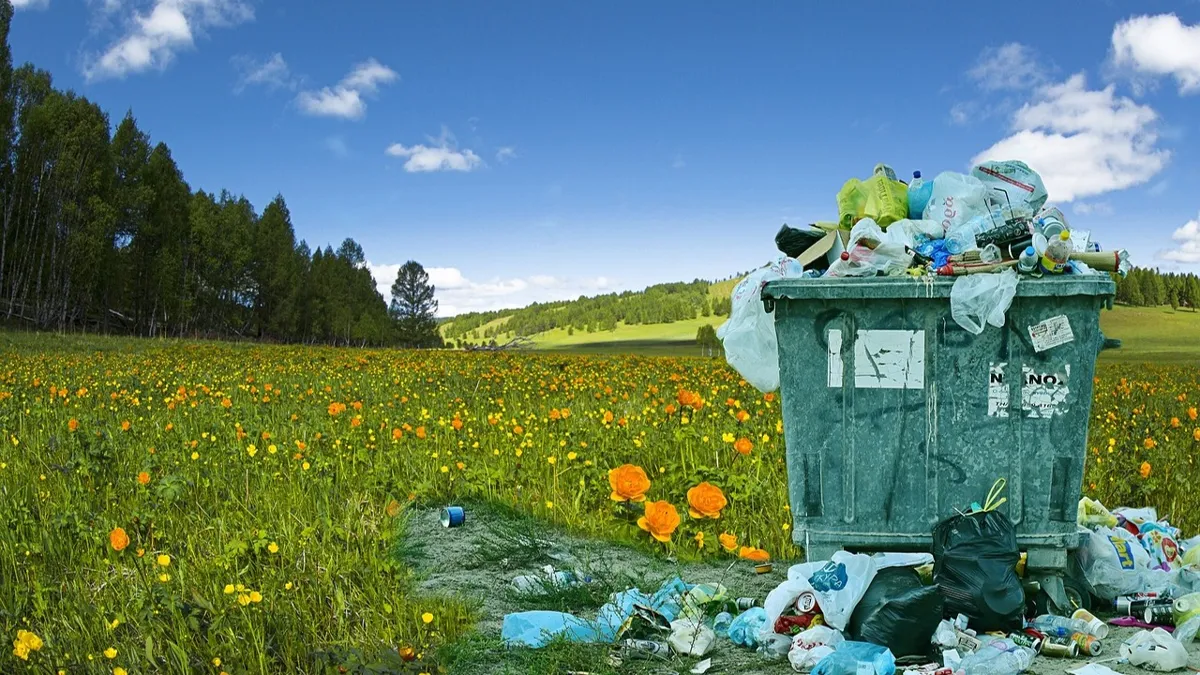 Мусорка, мусорный контейнер на поле на фоне голубого неба и деревьев