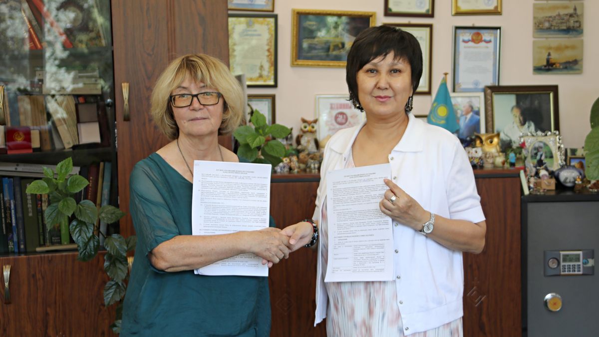 Ольга Гумирова и Гульнара Ситпаева, женщины пожимают руки, держат подписанный договор