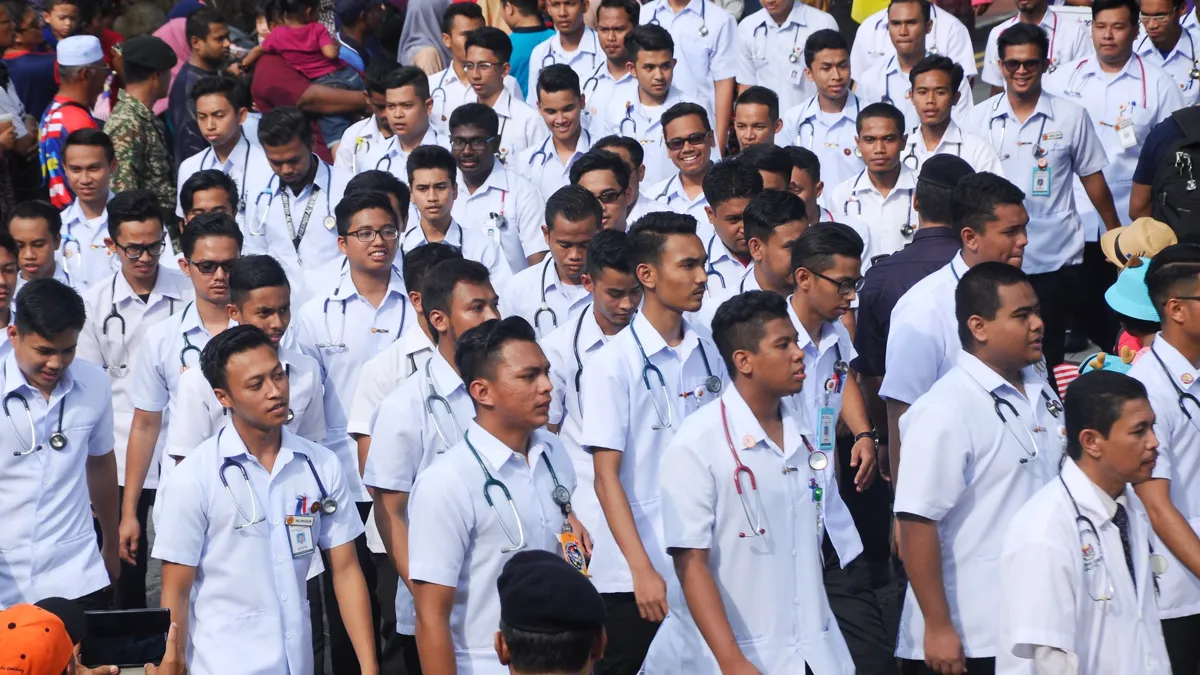 Малайзийские врачи идут маршем во время празднования Дня независимости Малайзии, толпа мужчин в белых халатах