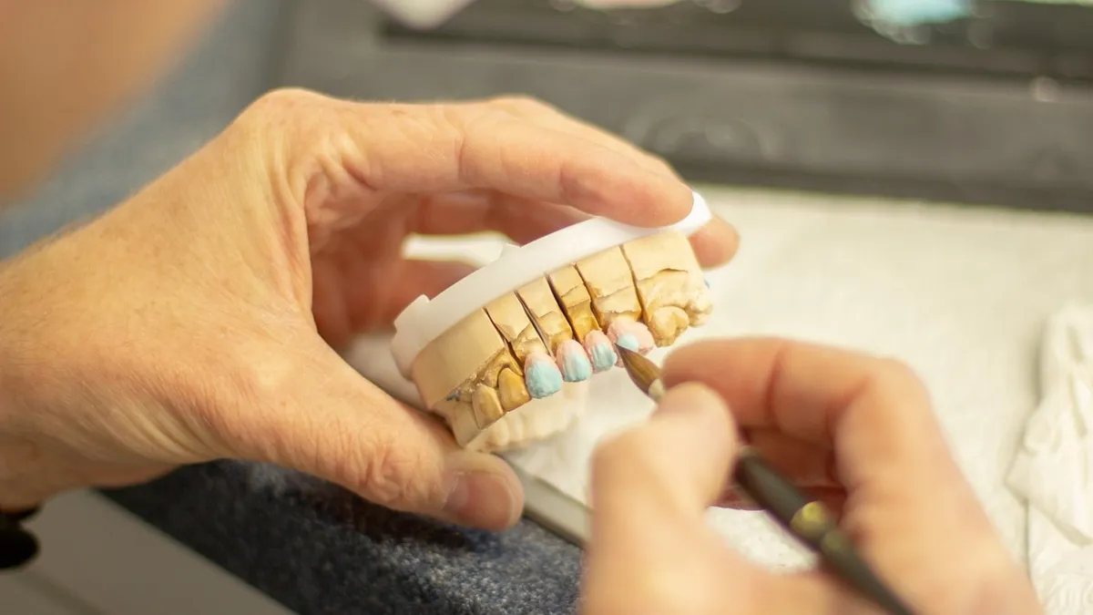 рука держит модель челюсти, замена зубов, импланты, коронки зубные