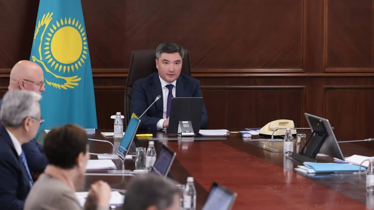 Олжас Бектенов за столом на фоне флага Казахстана проводит заседание правительства 