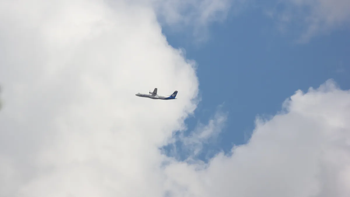 Самолёт ATR 72-500 , маленький самолет далеко в небе с облаками