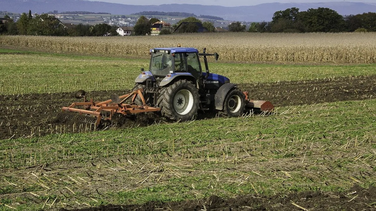 старый трактор в поле пашет землю