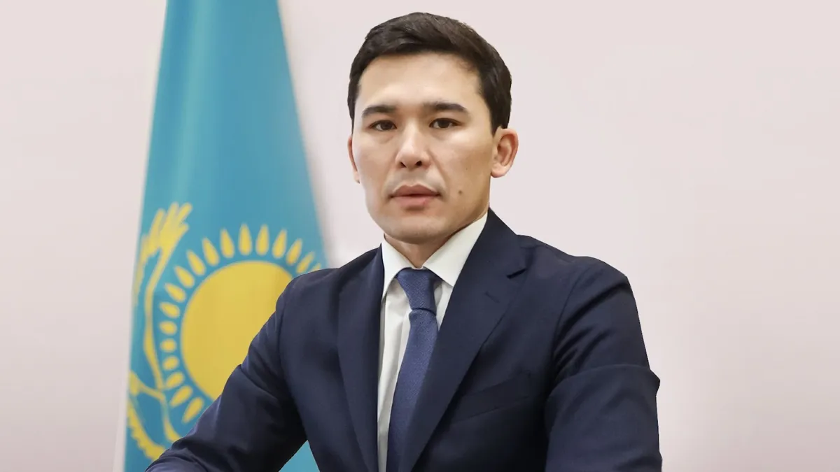 Ербол Мырзабосынов Ербол Мырзабосынов, мужчина в костюме на фоне флага Казахстана