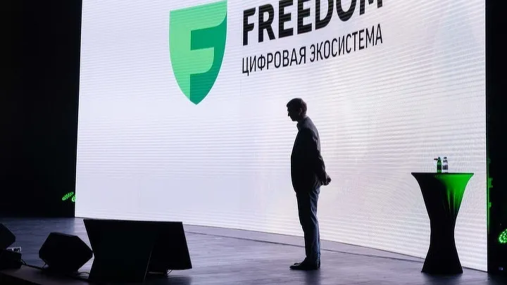 Тимур Турлов на сцене на фоне экрана с надписью «Freedom. Цифровая экосистема»