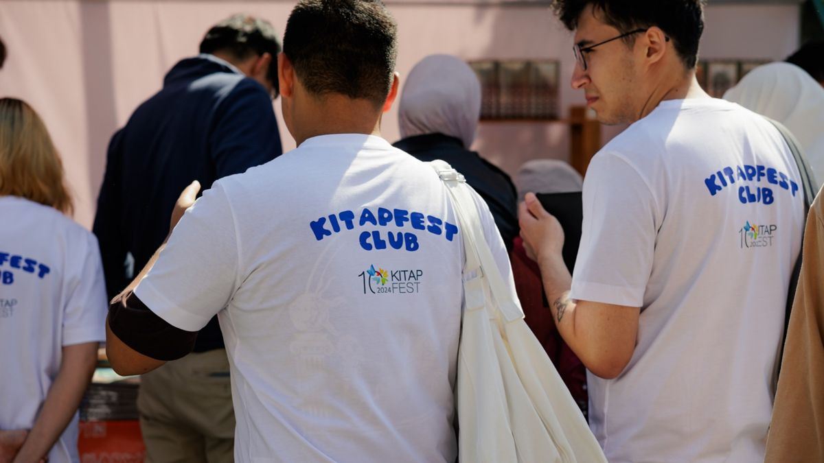   Волонтеры Kitap Fest, мужчины спиной в белых футболках с надписью