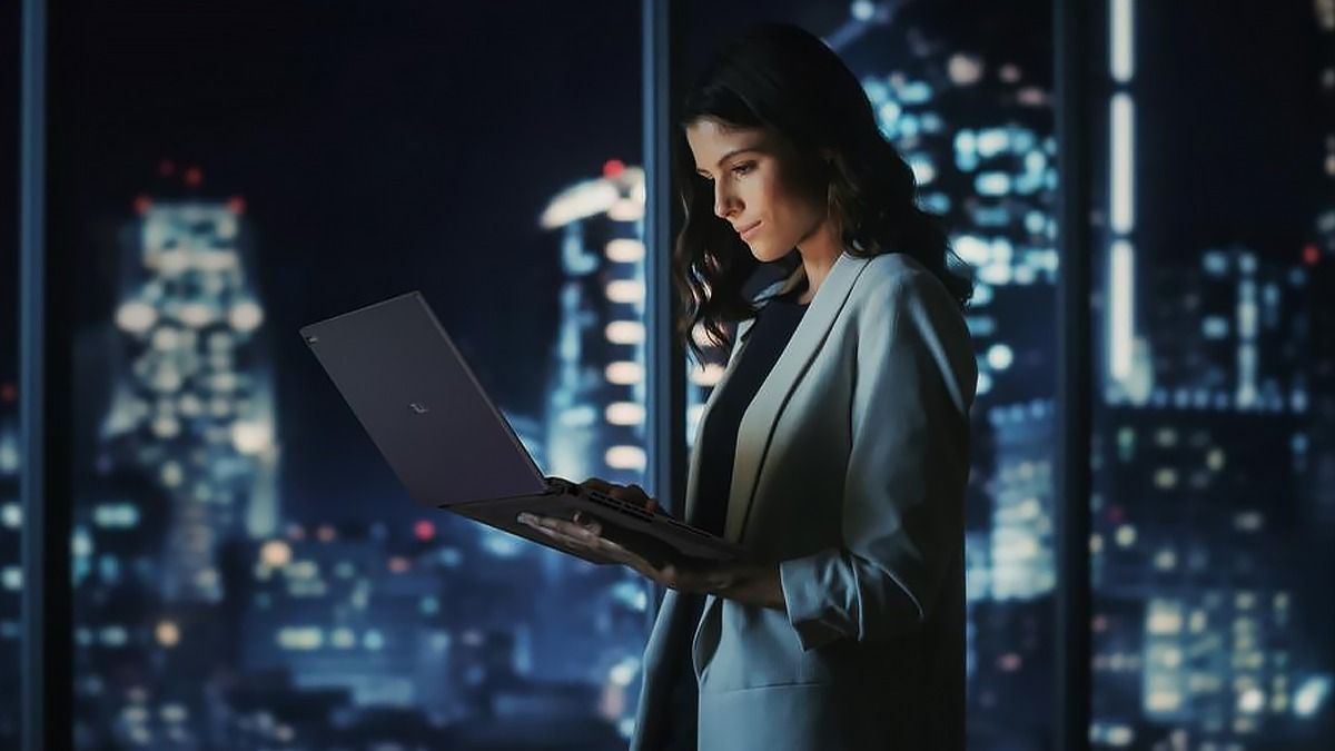 ASUS ExpertBook B3 Девушка на фоне окна с городским пейзажем, держит в руках ноутбук ASUS ExpertBook B3