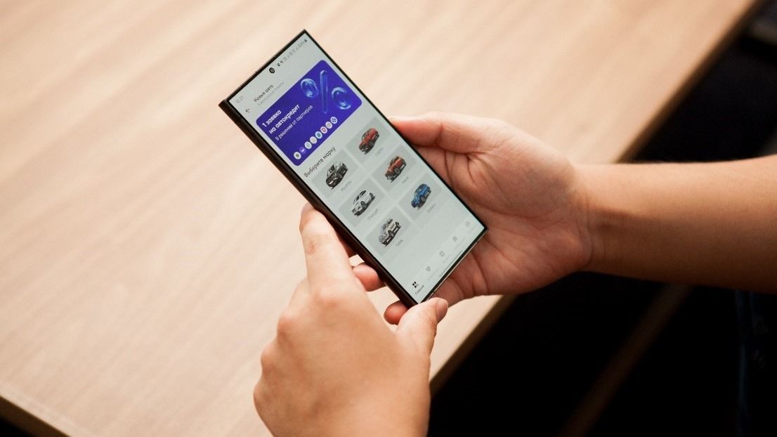 руки держат смартфон с приложением Mycar.kz