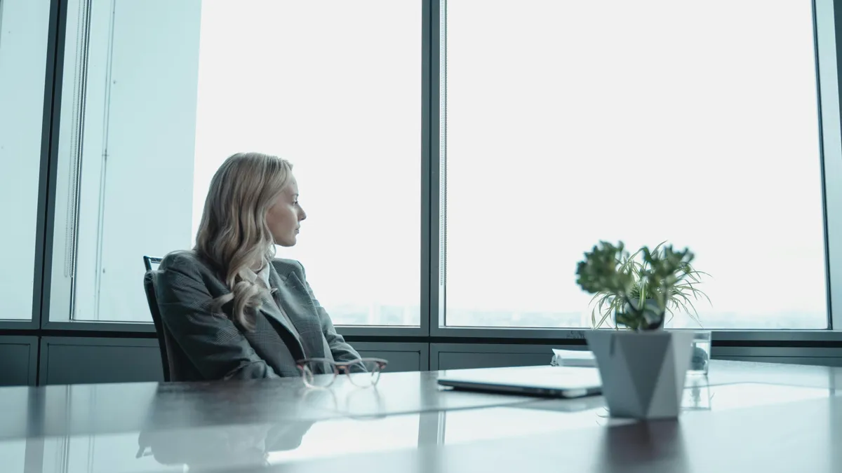 Девушка смотрит в окно в офисе