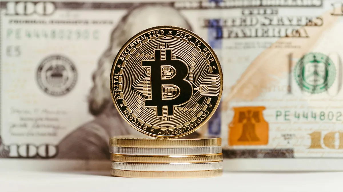 Биткоин и купюра номиналом 100 долларов