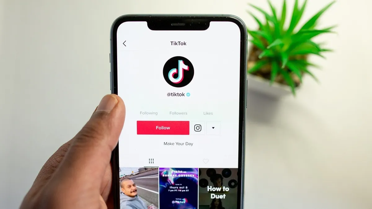Рука держит смартфон, на котором логотип Tiktok