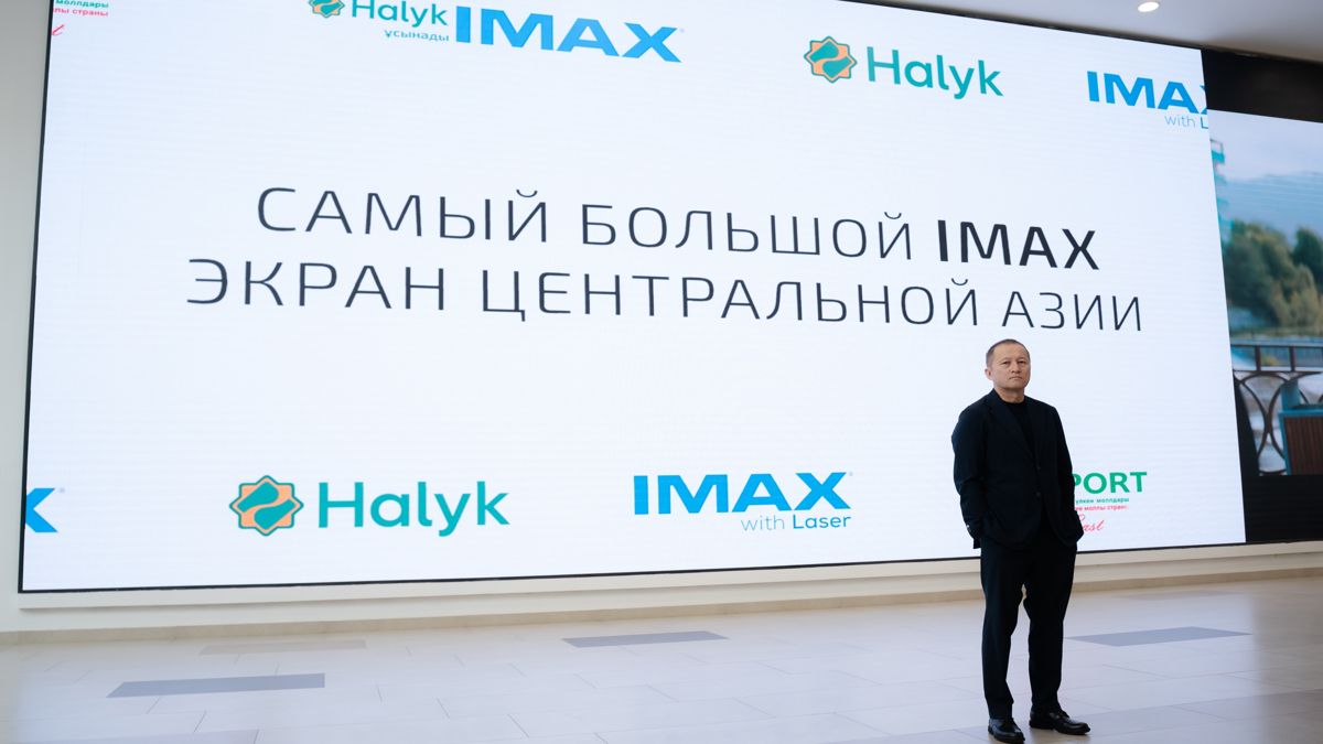 Алмаз Малдыбаев на фоне надписи про самый большой экран в ЦА