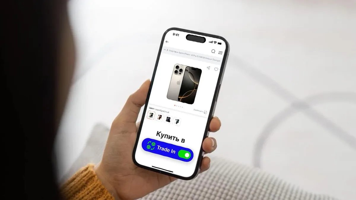 Все процессы проходят онлайн Рука держит смартфон с надписью «Купить в Trade In»