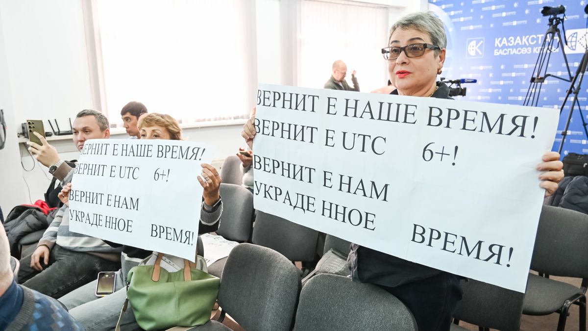 На пресс-конференции Женщина с плакатом Верните наше время! Верните украденное время!