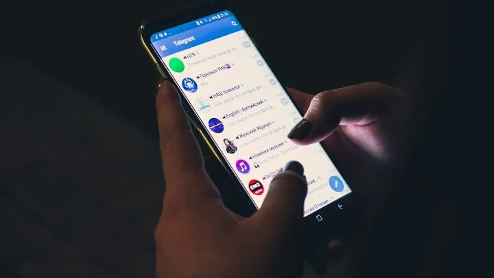 смартфон в руках с открытым Telegram на экране