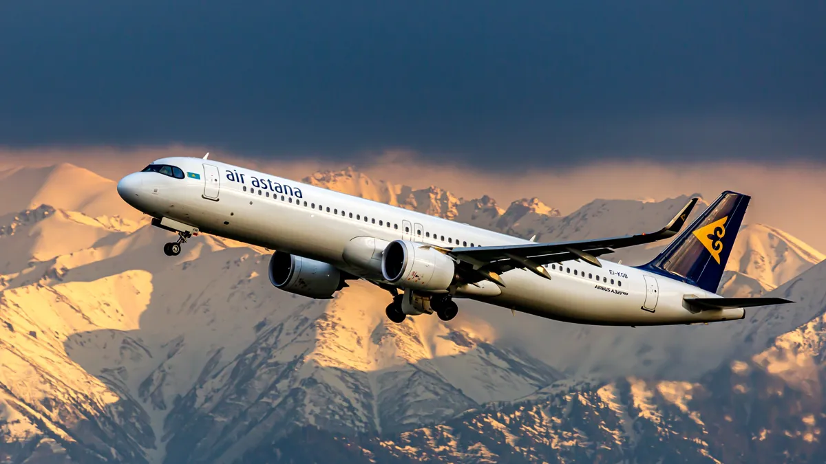 Самолет Air Astana в небе на фоне гор