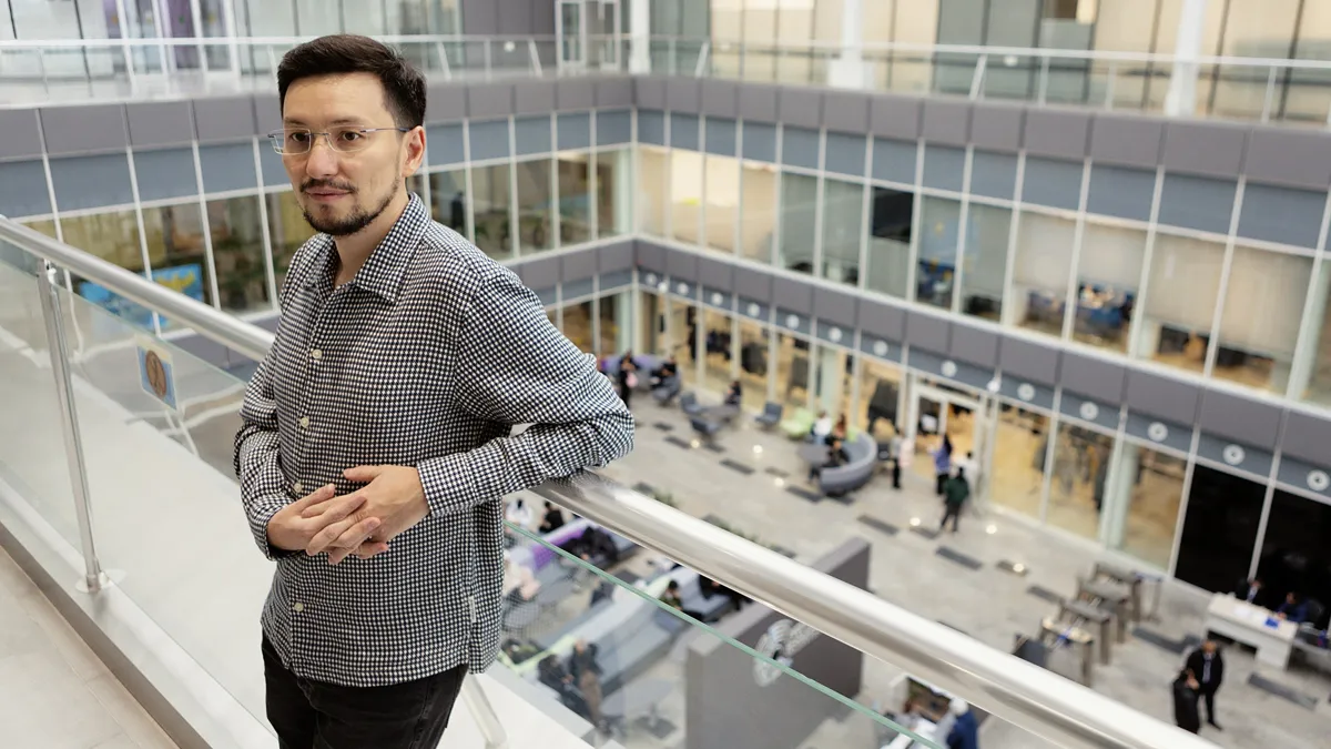 Айдар Арынгазин - основатель Doq.kz Мужчина в очках стоит в офисном пространстве