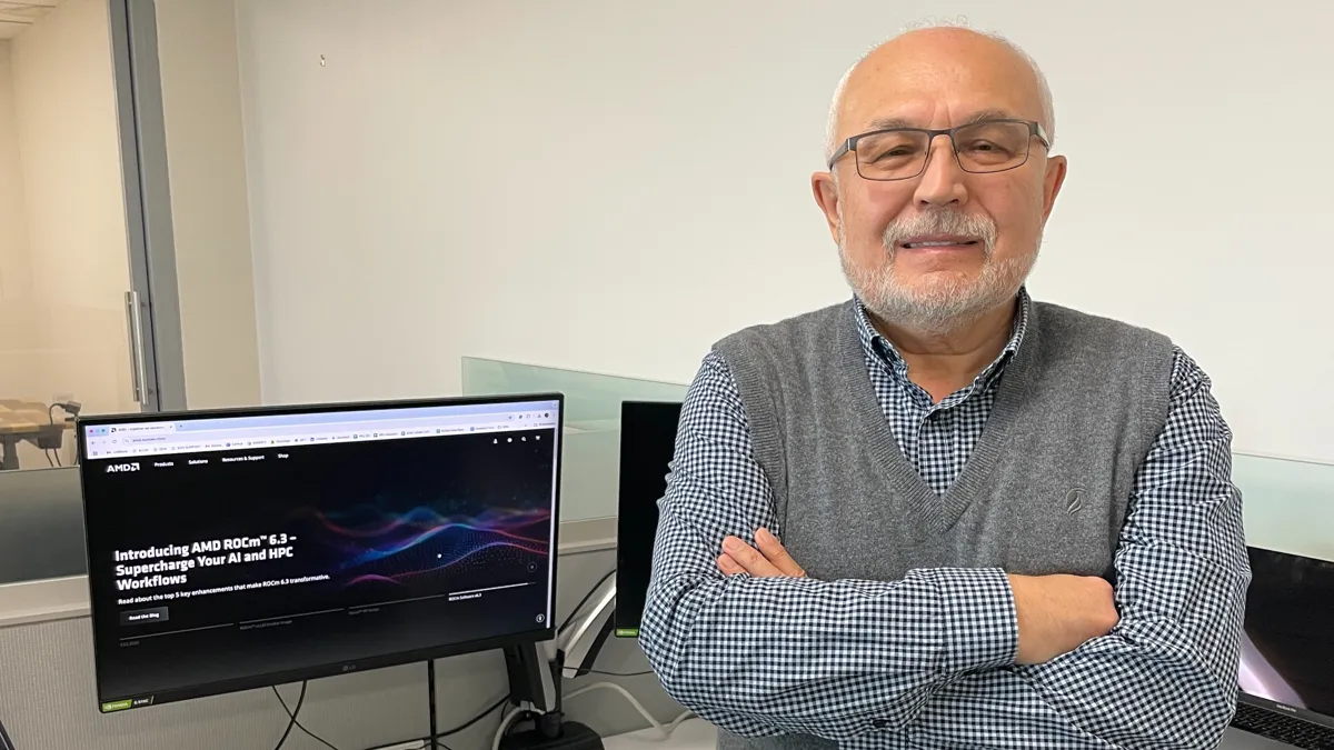 Тимур Палташев, старший менеджер в Artificial Intelligence Group, Advanced Micro Devices Лысый мужчина в очках перед компьютерным столом