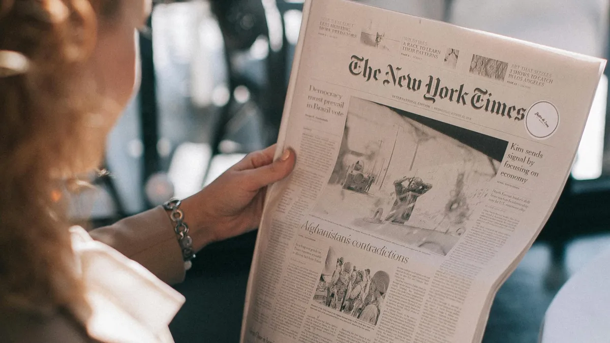 Девушка держит газету в руках The New York Times