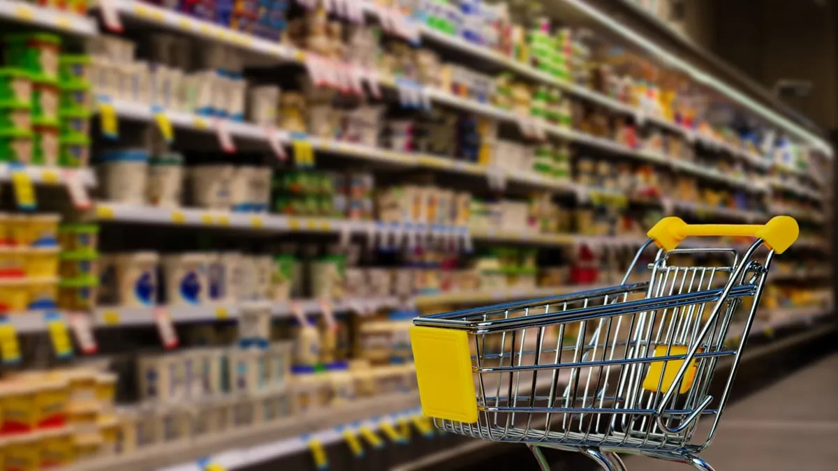 Пустая тележка супермаркета около полок с продуктами, инфляция, снижение потребительской уверенности, рост цен на продукты