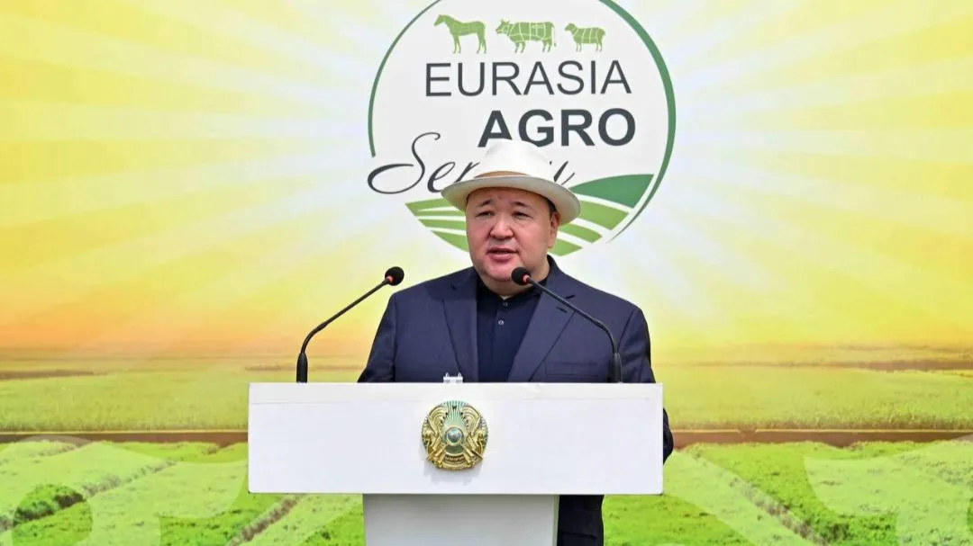 Ерлан Мукашев стоит на трибуне на фоне логотипа Eurasia Agro Semey