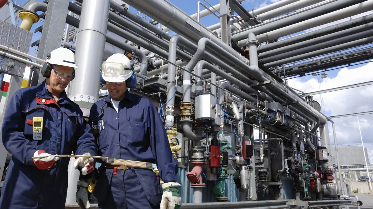 Два работника отрасли внутри установки нефти и газа, трубопроводный главный топливный склад, нефтепровод