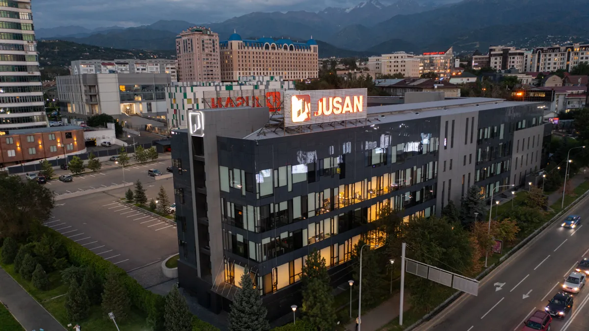 Здание с вывеской Jusan на крыше в Алматы