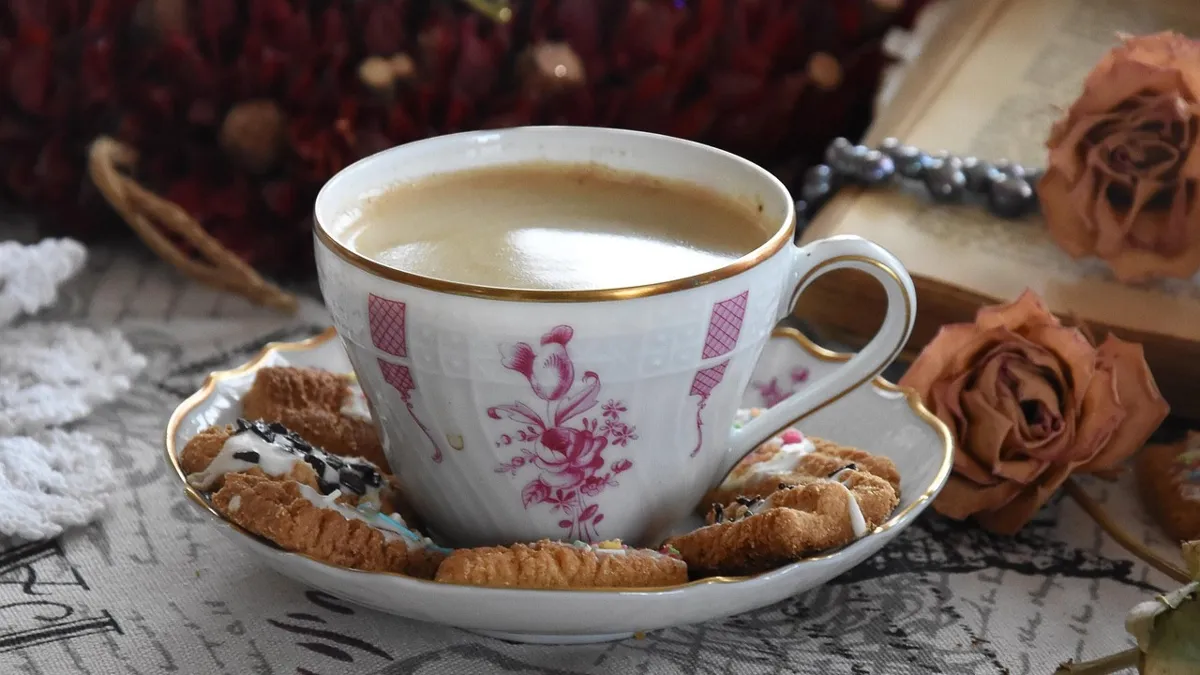 Чашка кофе с молоком, на блюдце печенье
