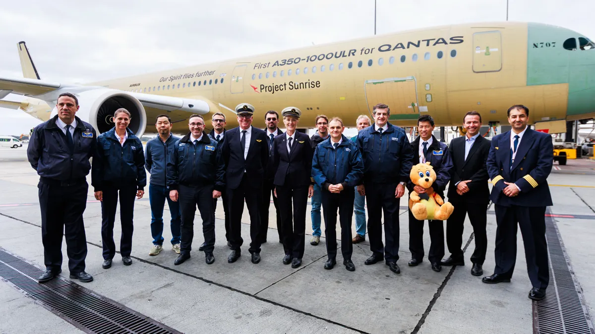 Экипаж и сотрудники компаний Airbus и Qantas на фоне самолета перед полетом