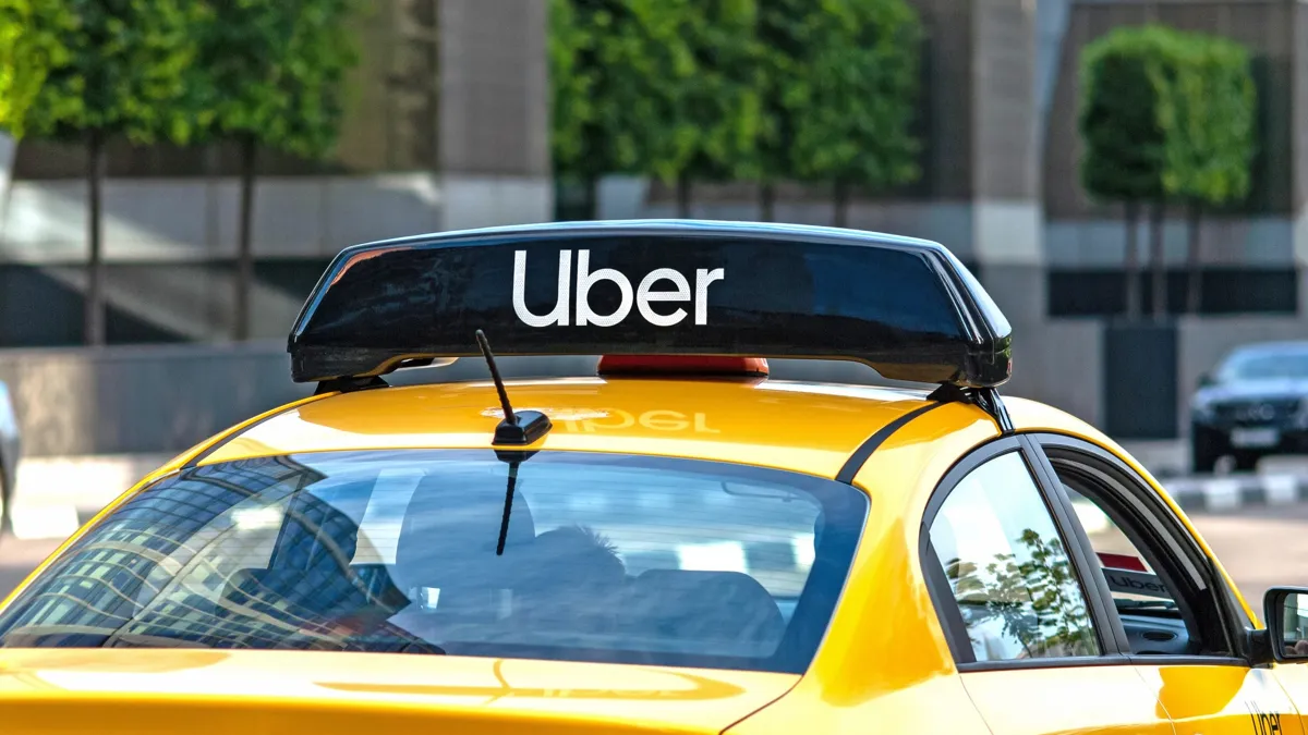 Желтое такси на улице с логотипом Uber сверху - Москва, 09.09.2020